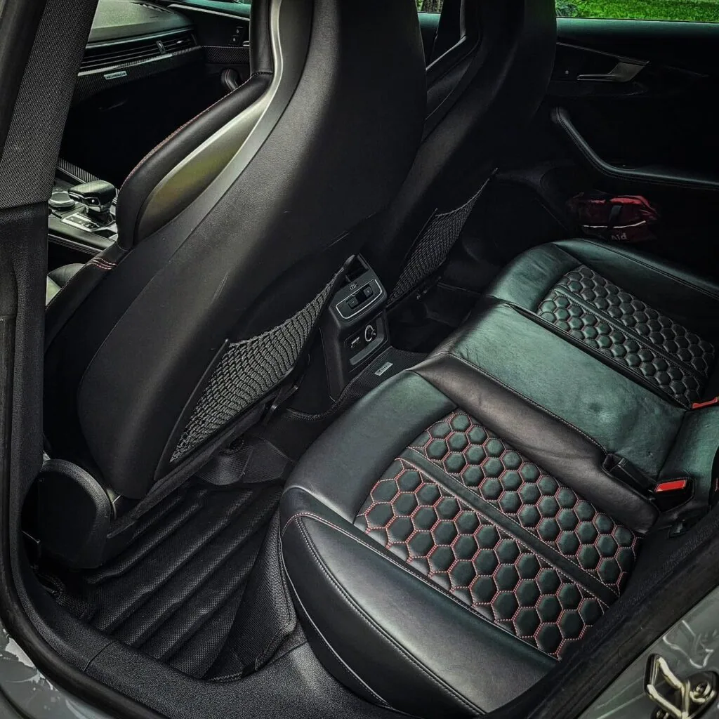 Rear seat of an Audi RS with black honeycomb-stitched leather and red accents after interior detailing