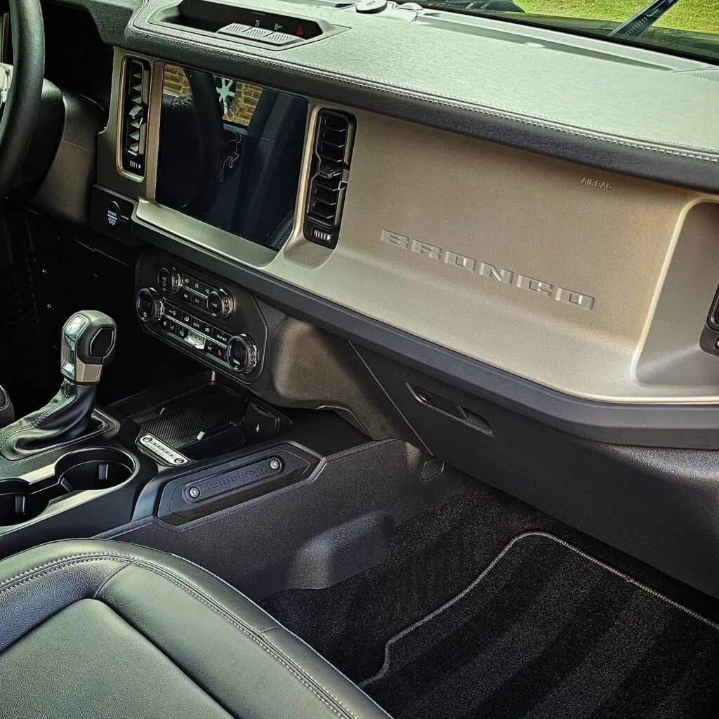 Ford Bronco dashboard with Bronco lettering, center console, and clean black floor mats after interior detailing