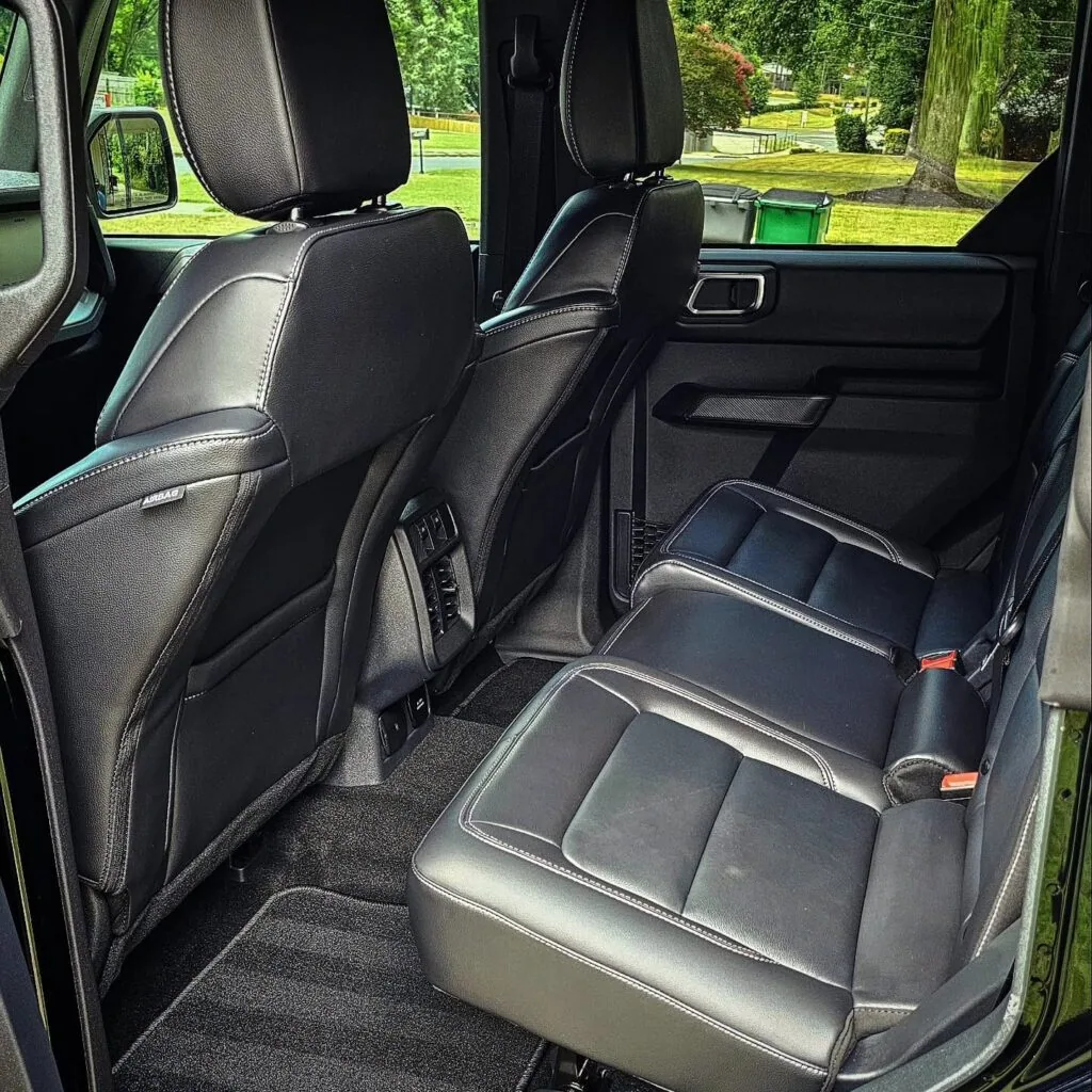 Rear black leather seats and clean carpet inside a Ford Bronco viewed through the open rear door