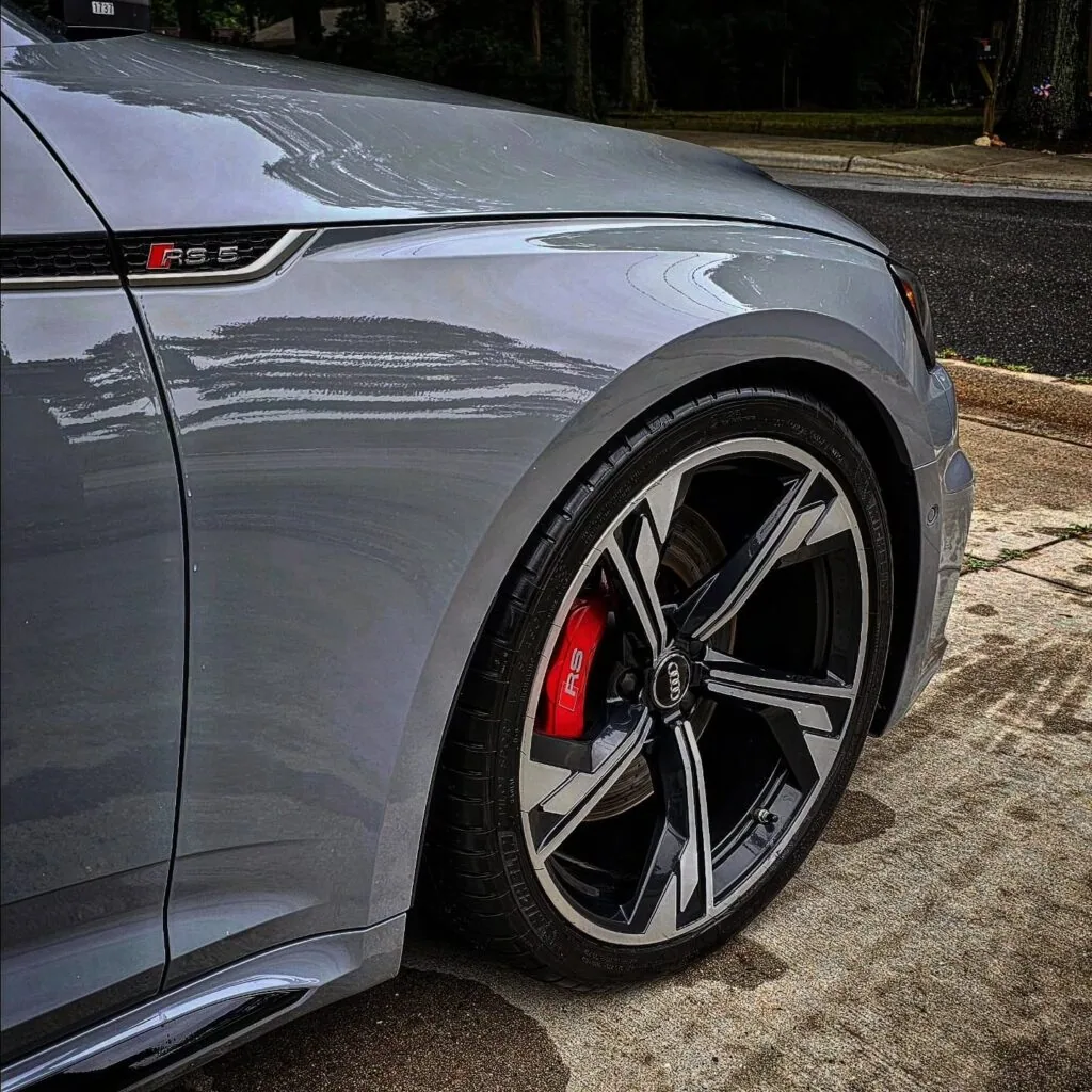 Close-up of a gray Audi RS5 front fender and polished alloy wheel with red RS brake caliper after detailing