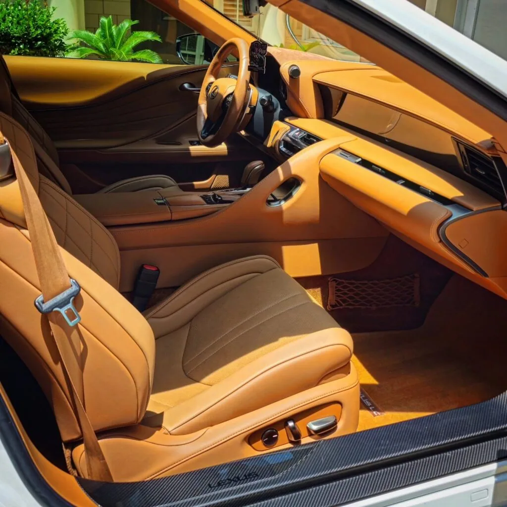 Passenger side view of a white Lexus LC interior with clean tan leather seats, dashboard, and steering wheel