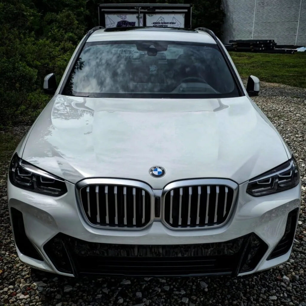 Front view of a white BMW X3 SUV with a glossy hood and clean kidney grilles parked on gravel