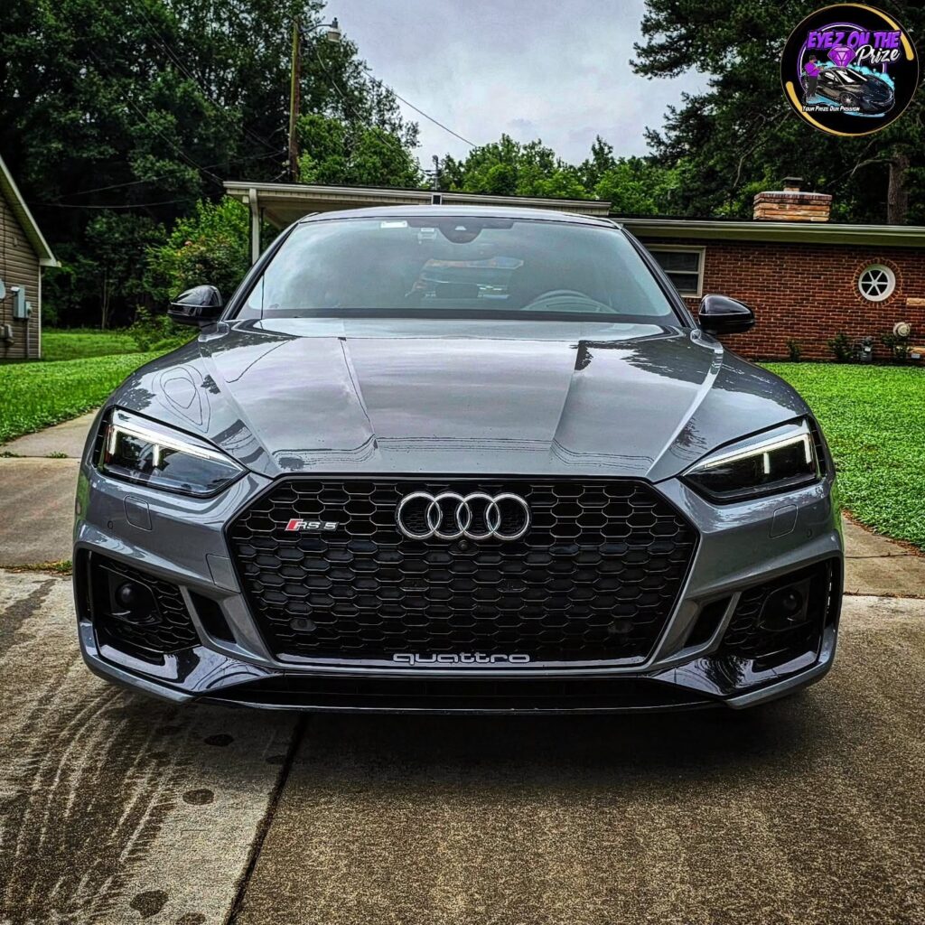 Front view of a Nardo gray Audi RS5 with honeycomb grille parked on a residential driveway after detailing