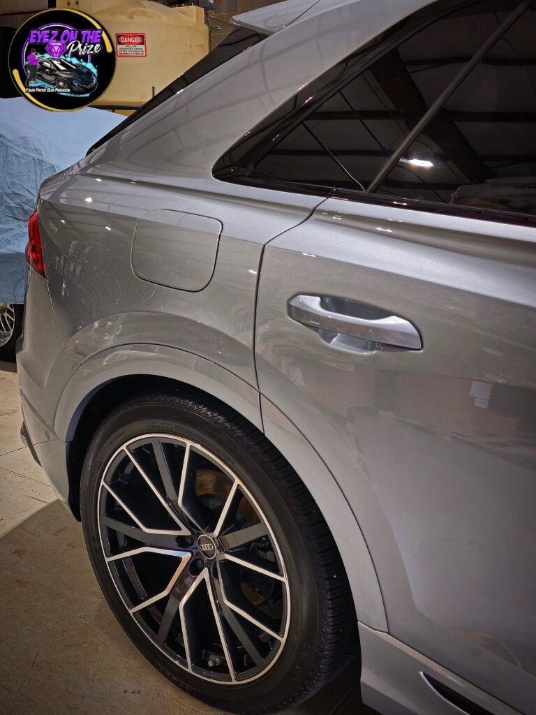 Rear quarter panel and black machined wheel of a gray Audi SQ8 after detailing inside a shop