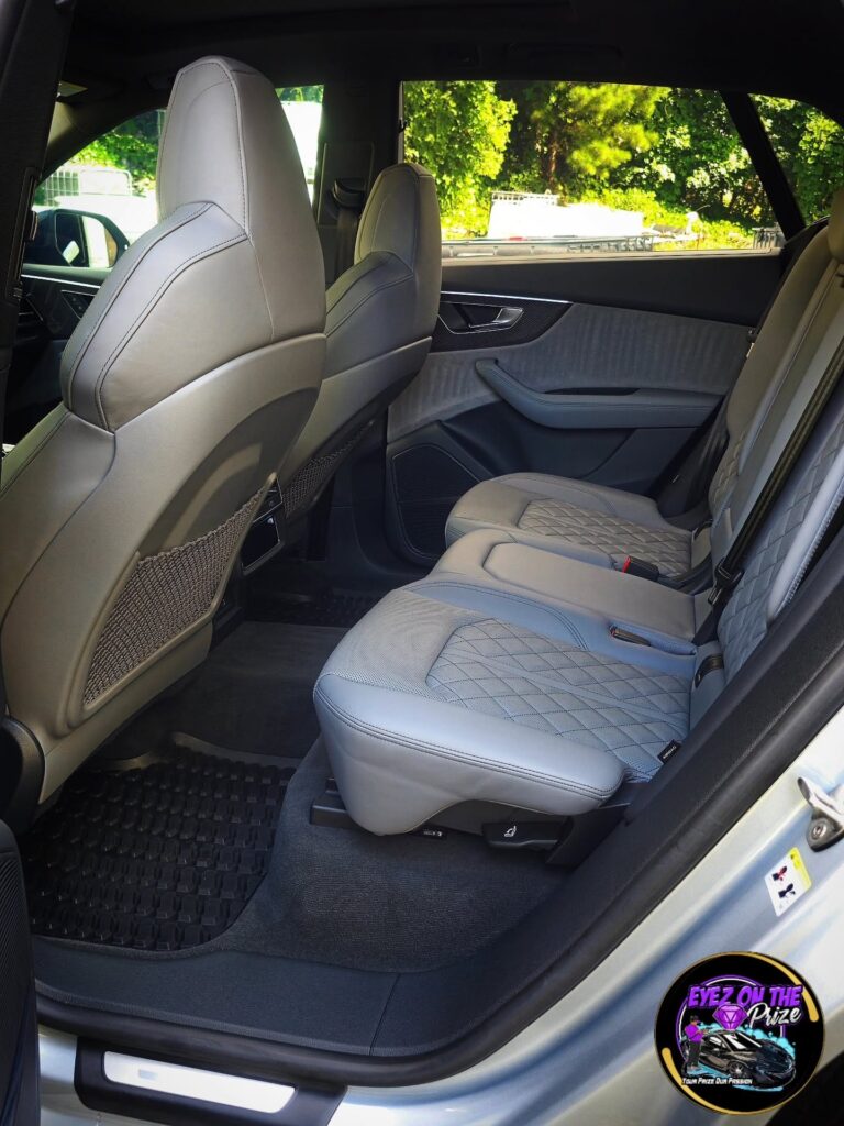 Rear seat area of an Audi SQ8 with gray diamond-stitched leather seats and clean black floor mats