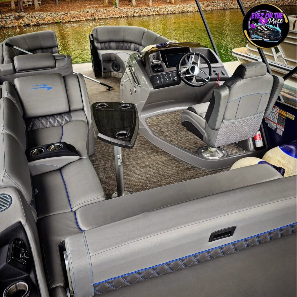 Clean gray pontoon boat interior with blue-stitched upholstery, helm seat, steering console, and table at a dock