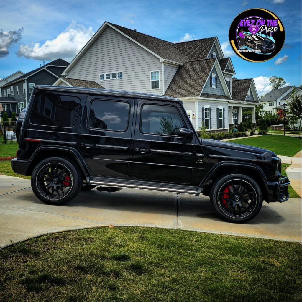 Black Mercedes-AMG G63 SUV parked in a residential driveway after detailing, side profile view with red brake calipers