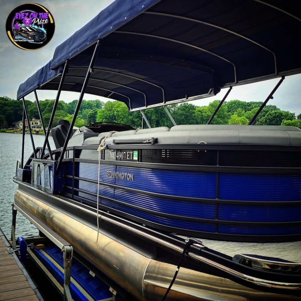 Blue Bennington pontoon boat with navy bimini top on a boat lift at a lake dock after detailing
