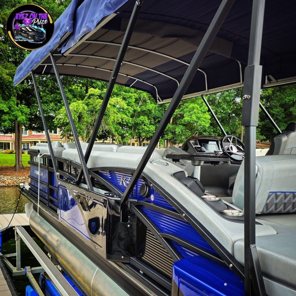 Blue pontoon boat on a lift at a dock with gray upholstered seats, helm, and navy bimini top