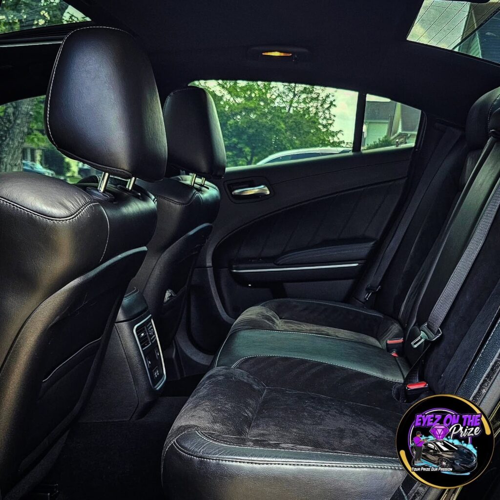 Rear seat of a Dodge Charger with clean black leather and suede upholstery after interior detailing
