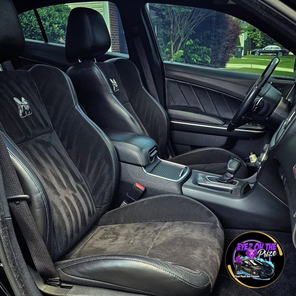 Black Dodge Charger Scat Pack front interior with cleaned suede and leather seats, Super Bee logo visible on seatbacks.