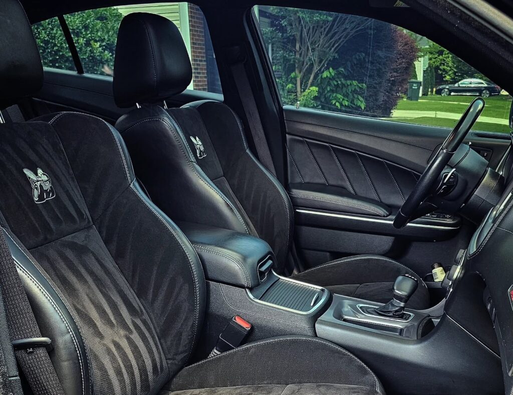 Black Dodge Charger Scat Pack front interior with cleaned suede and leather seats, Super Bee logo visible on seatbacks.