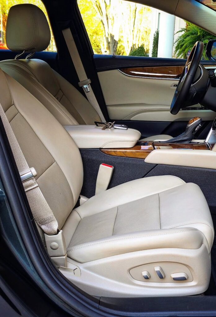 Front passenger view of a Cadillac XTS interior with clean cream leather seats, wood trim, and detailed console in Charlotte