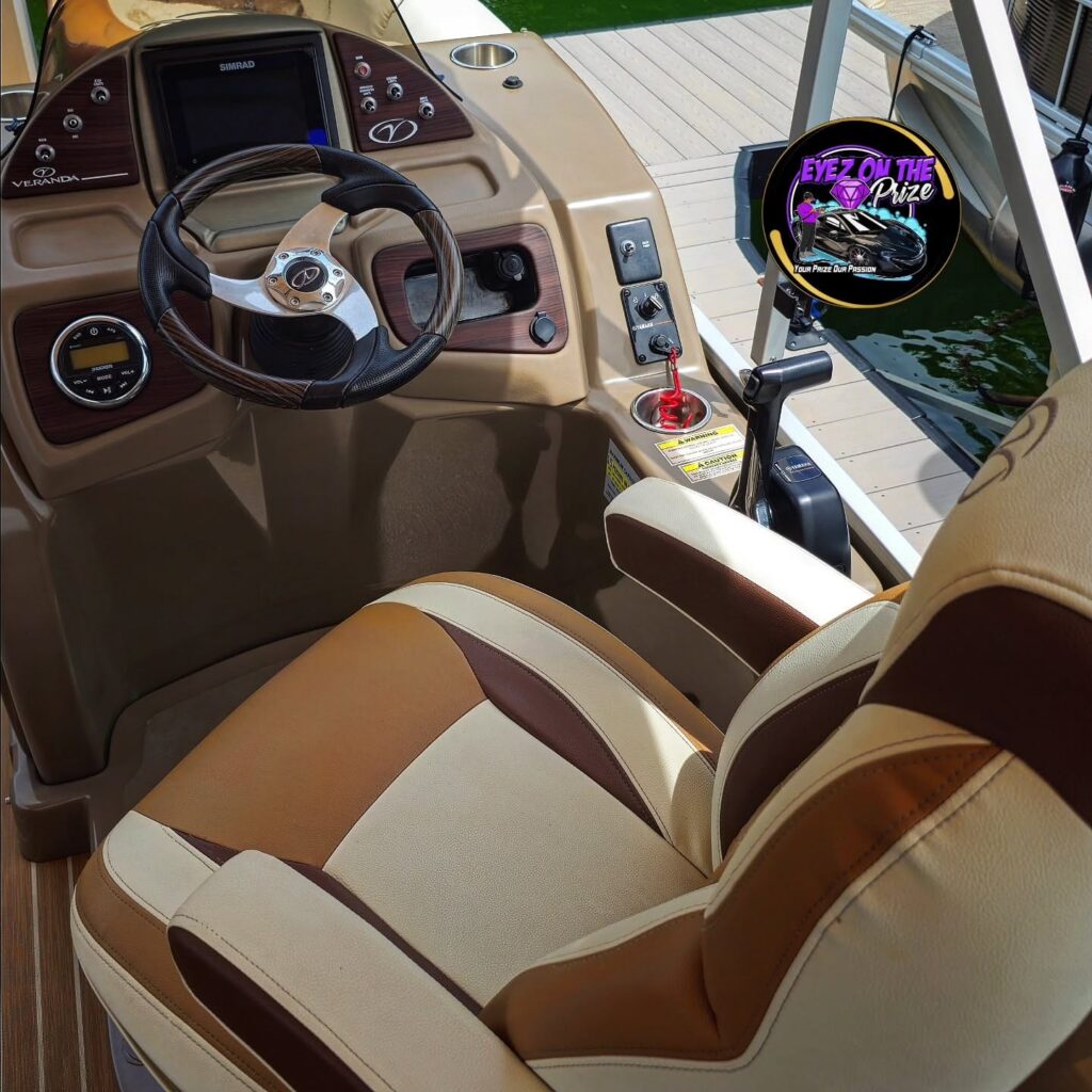 Clean helm of a Veranda pontoon boat with tan vinyl captain seat, wood-trim steering wheel, and Simrad display at a dock.
