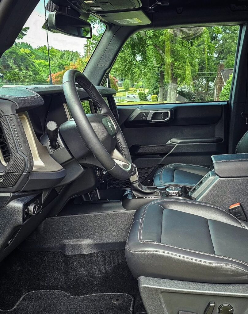 Driver side view of a Ford Bronco interior with cleaned black leather seats, steering wheel, and vacuumed carpet