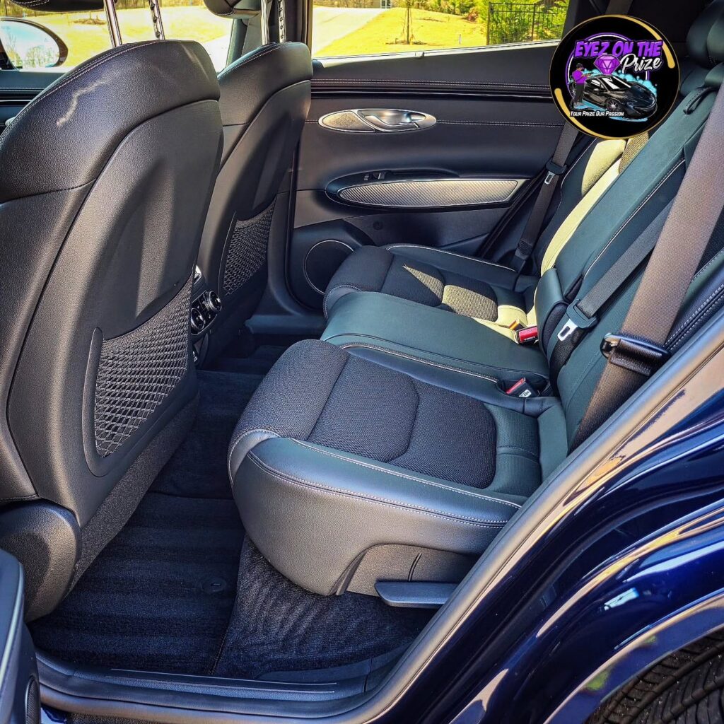 Clean rear seats, door panel, and carpet of a blue Genesis GV70 SUV after interior detailing