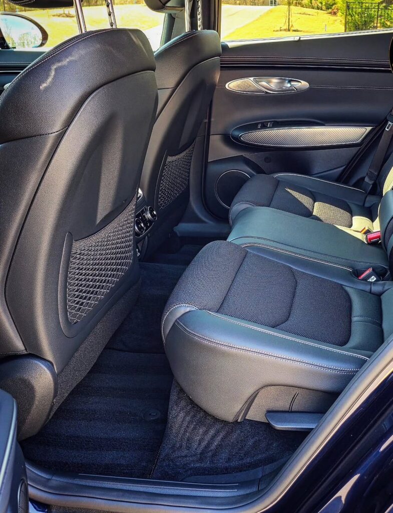 Clean rear seats, door panel, and carpet of a blue Genesis GV70 SUV after interior detailing