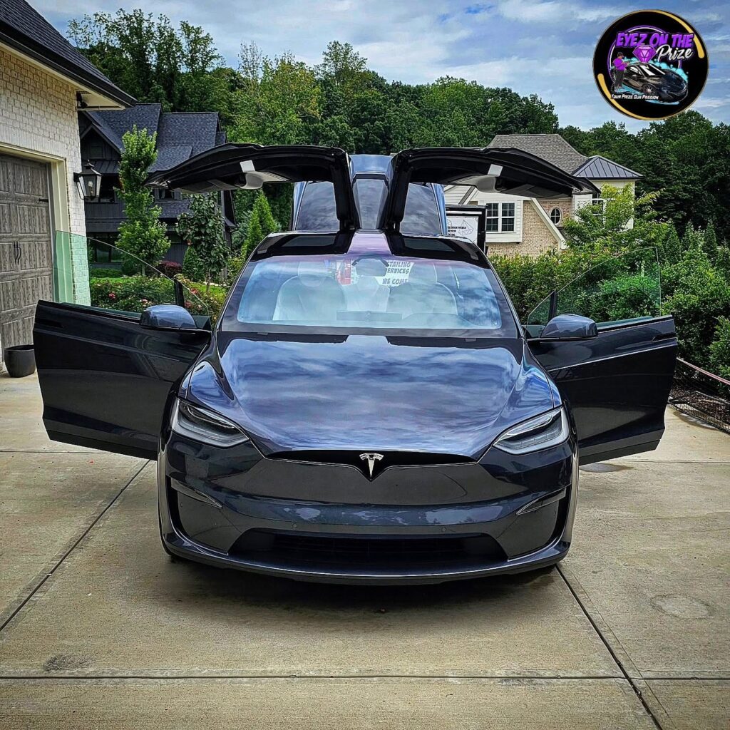 Gray Tesla Model X with falcon wing doors open on a residential driveway after detailing in Charlotte NC