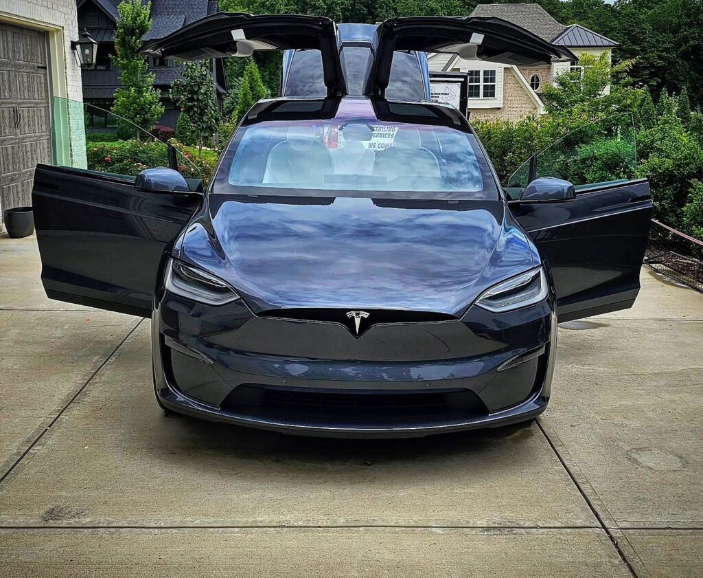 Gray Tesla Model X with falcon wing doors open on a residential driveway after detailing in Charlotte NC