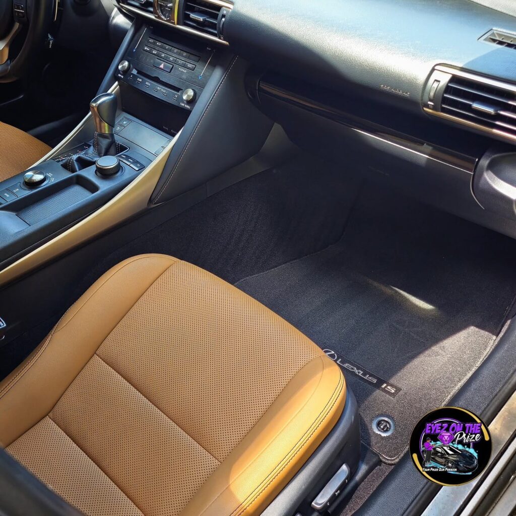 Clean tan leather passenger seat and black carpet floor mat inside a Lexus IS after interior detailing