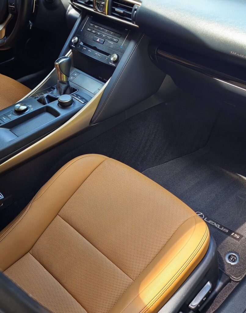 Clean tan leather passenger seat and black carpet floor mat inside a Lexus IS after interior detailing
