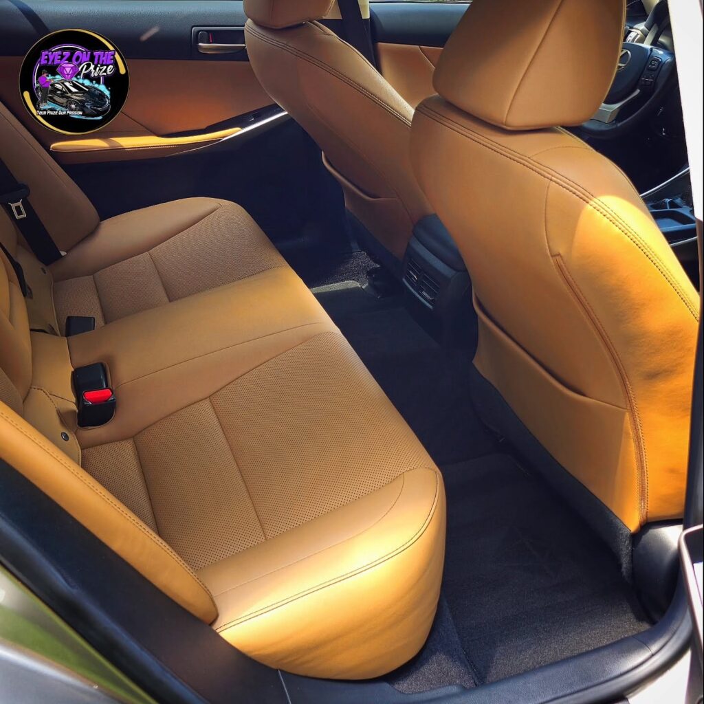 Clean tan leather rear seats and black carpet inside a Lexus sedan after interior detailing