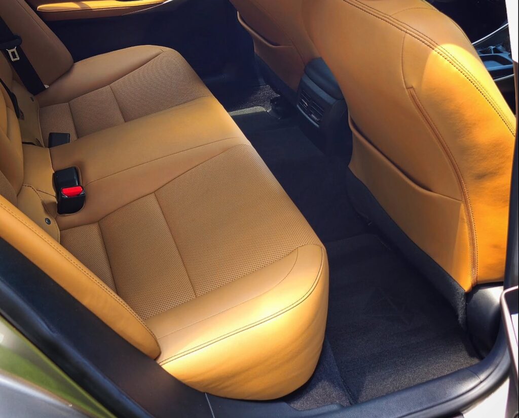 Clean tan leather rear seats and black carpet inside a Lexus sedan after interior detailing