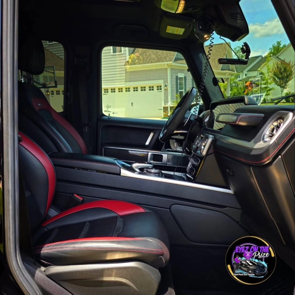 Passenger side view of a Mercedes G-Class interior with clean red and black leather seats and dashboard.