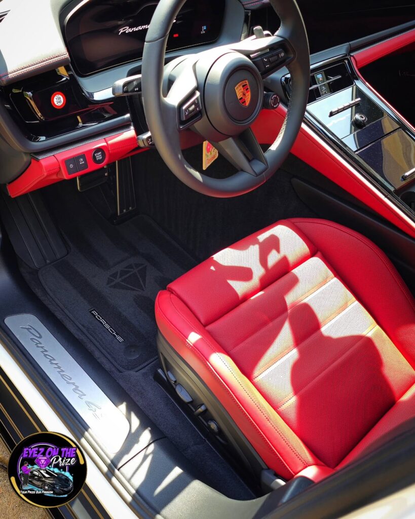 Driver seat area of a Porsche Panamera 4 with red leather seat, steering wheel, and clean black floor mat