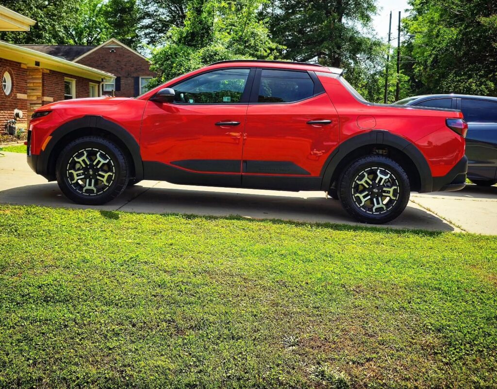 Red Hyundai Santa Cruz pickup shown in full side profile on a residential driveway after detailing