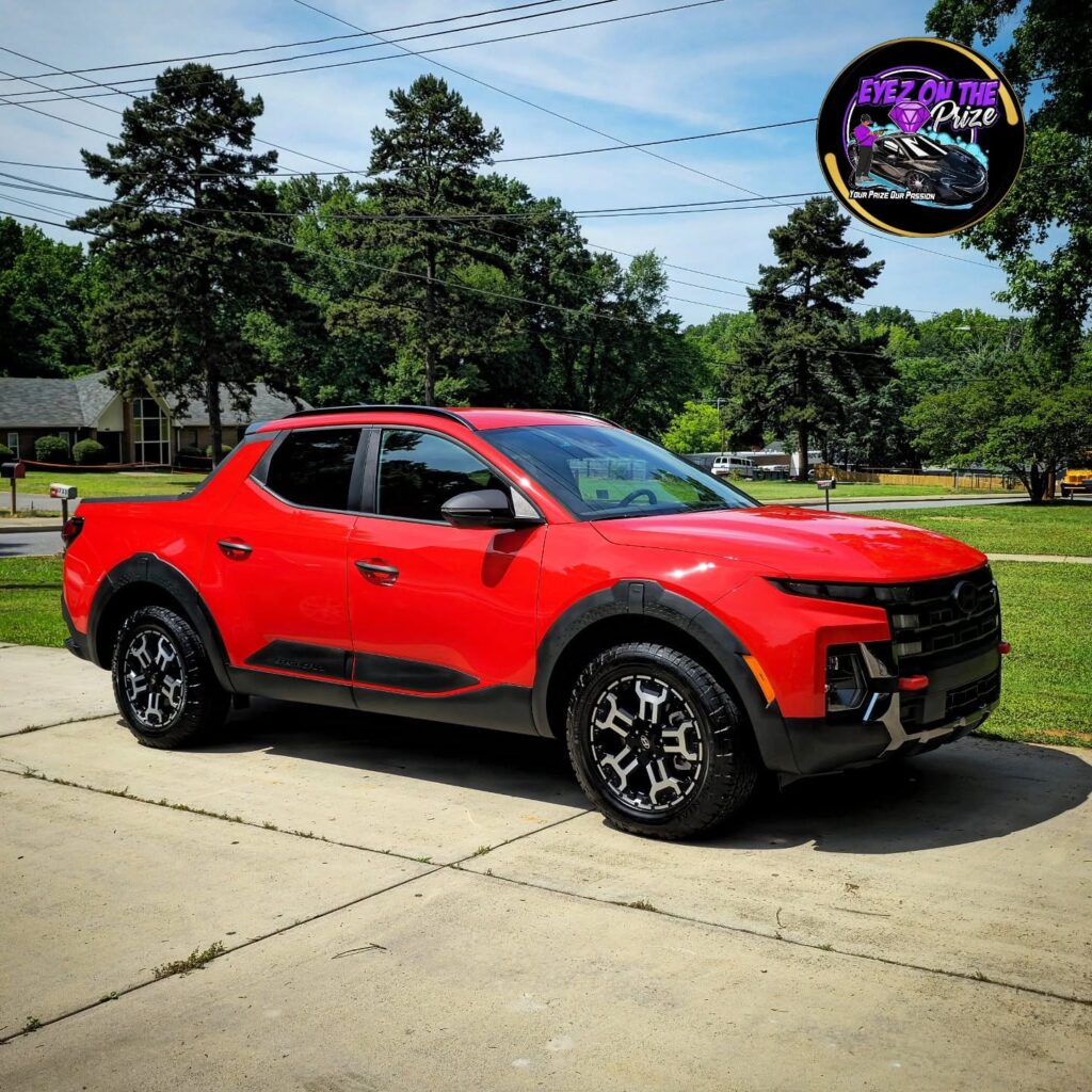 Red Hyundai Santa Cruz pickup parked on a concrete driveway after detailing, shown in full side profile with glossy paint.