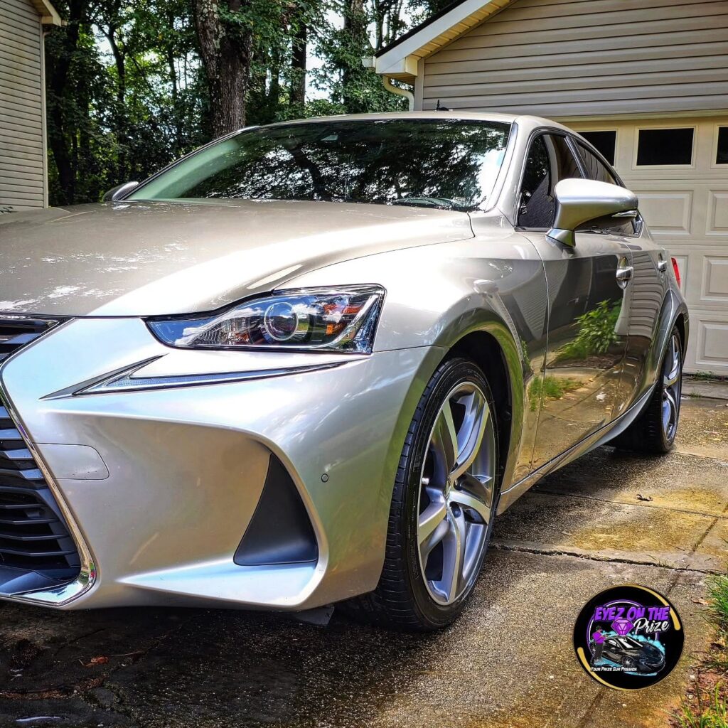 Front quarter view of a silver Lexus IS sedan with polished paint parked in a residential driveway
