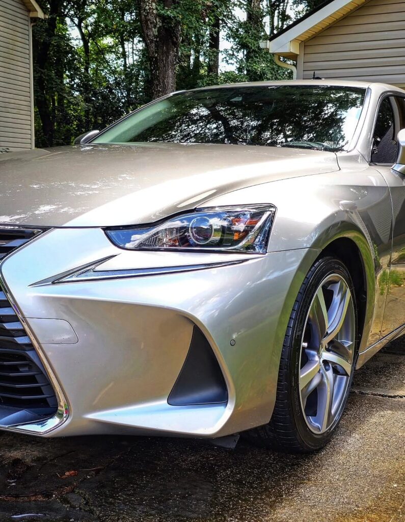 Front quarter view of a silver Lexus IS sedan with polished paint parked in a residential driveway