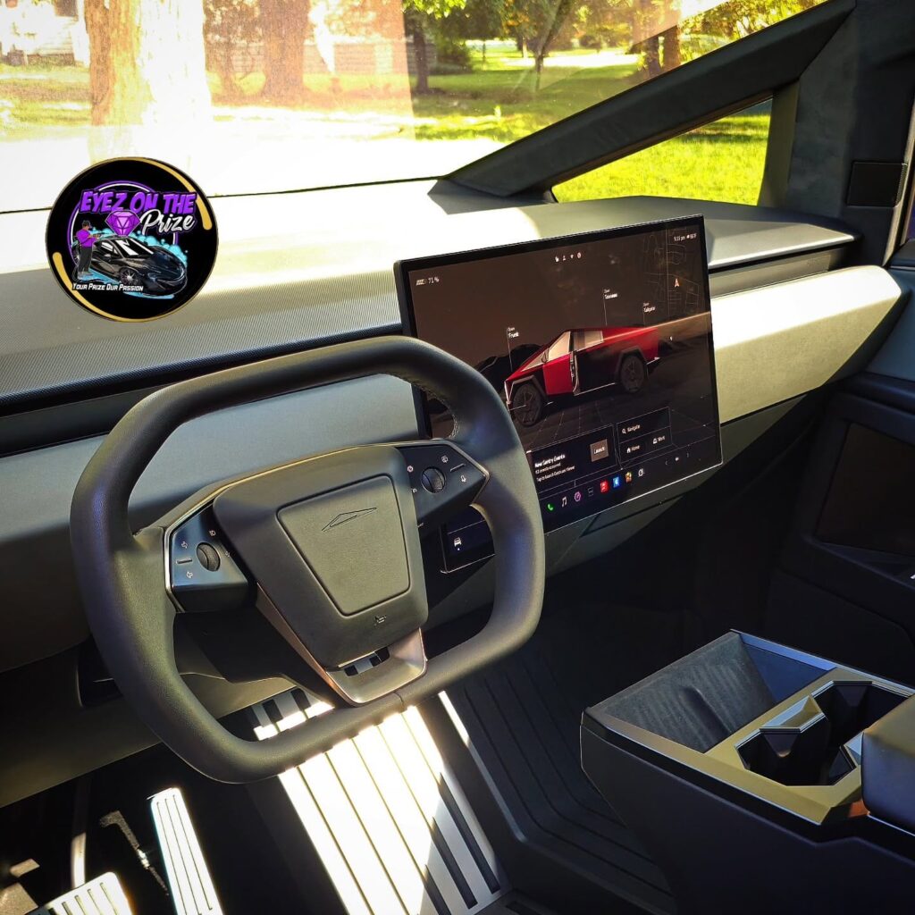 Tesla Cybertruck interior with yoke steering wheel, center touchscreen, and clean dashboard and console