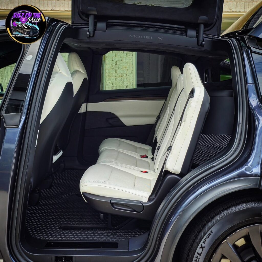 Tesla Model X rear white leather seats seen through open falcon wing door after interior detailing