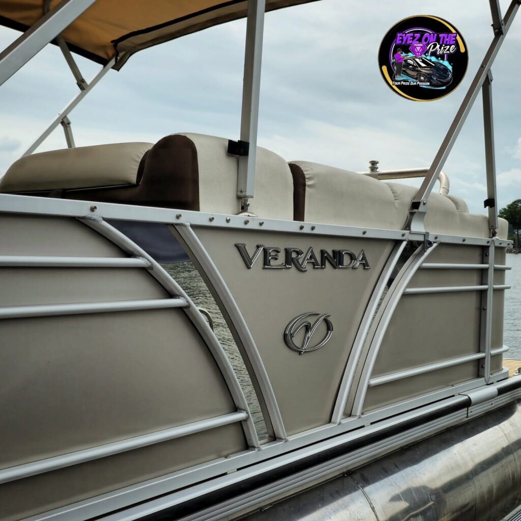 Side panel of a tan Veranda pontoon boat with clean fencing, rails, and upholstery, docked on a lake