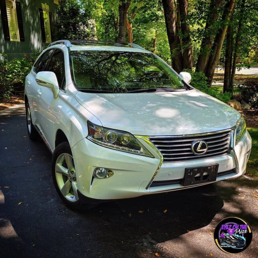 Front three-quarter view of a white Lexus RX SUV parked on a shaded residential driveway after detailing in Charlotte.