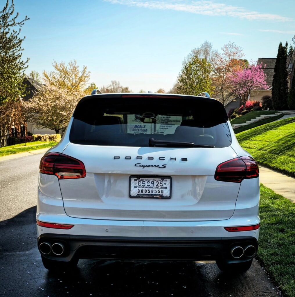 Rear view of a white Porsche Cayenne S parked on a residential street after detailing in Charlotte, NC.